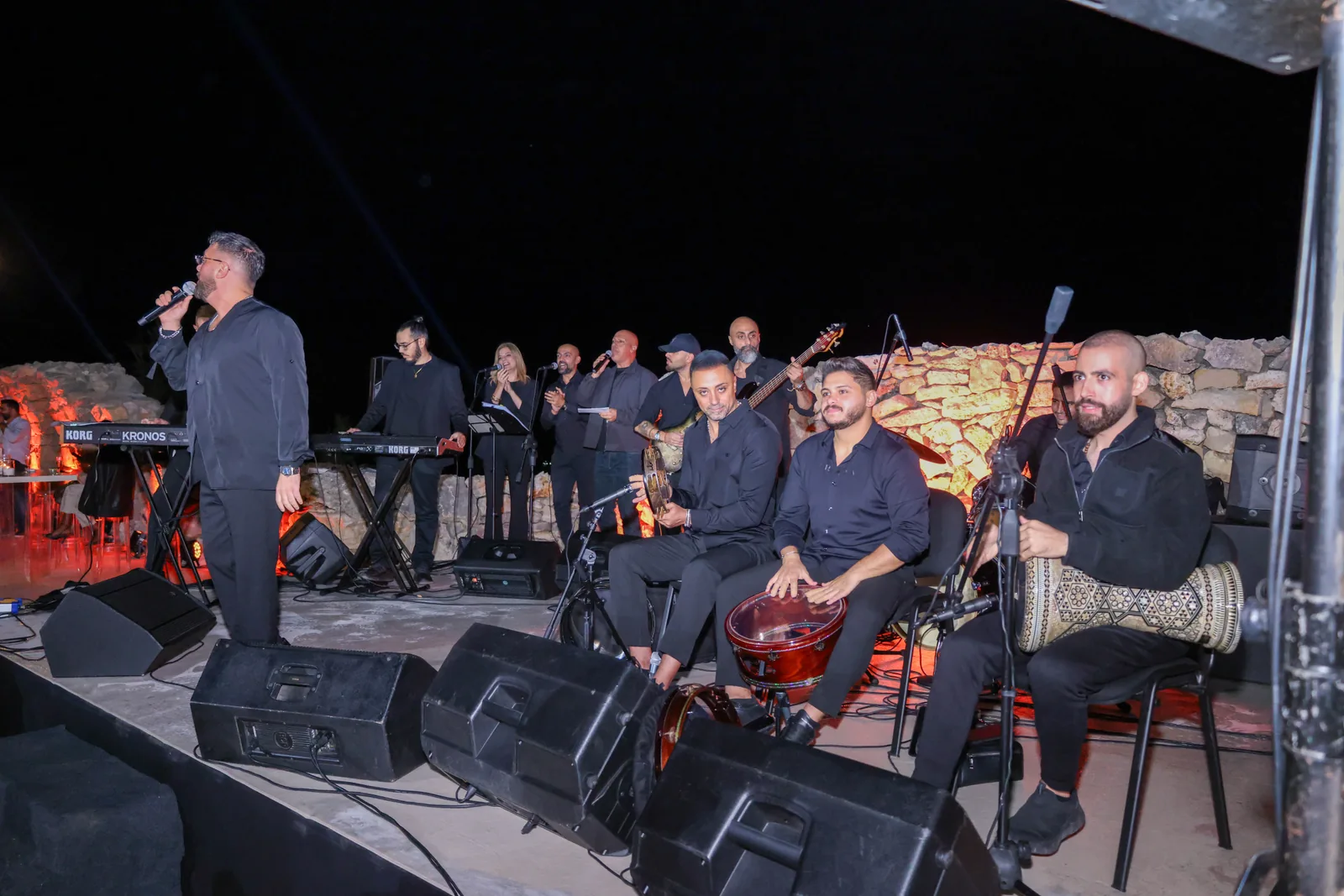 A singer and musicians performing on stage beside the stone ruins at the 1000M launch