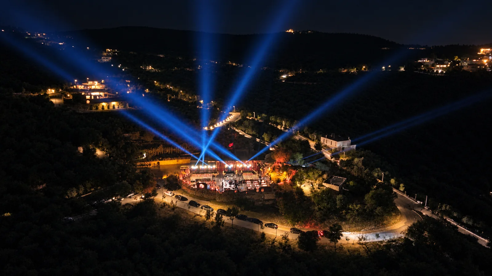 Aerial view of the 1000M launch celebration, with blue beams above the illuminated venue at night
