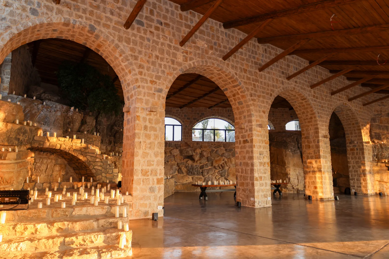 Warm evening light across the stone arches, timber ceiling and candlelit staircase at 1000M